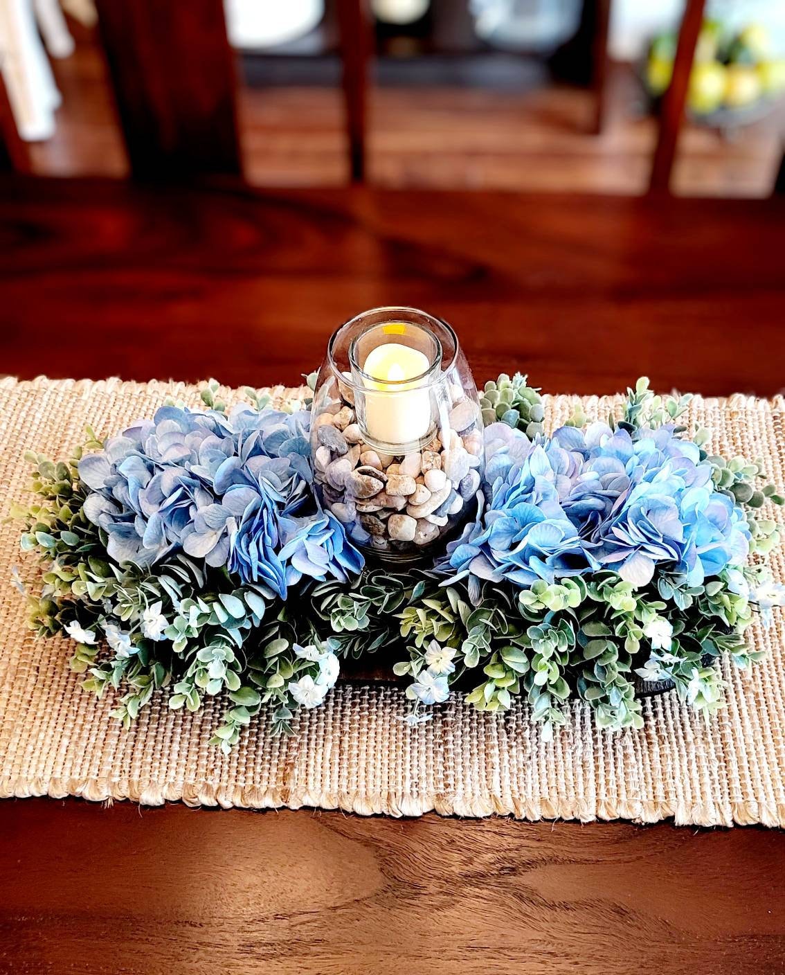 Blue Hydrangea Arrangement Rustic Black Bowl Farmhouse Table Centerpiece Wooden Dough Bowl Design Country Home Decor Natural Stone Elements Votive Candle Display Glass Vase Feature Nineteen Inch Size Traditional Modern Blend Dining Table