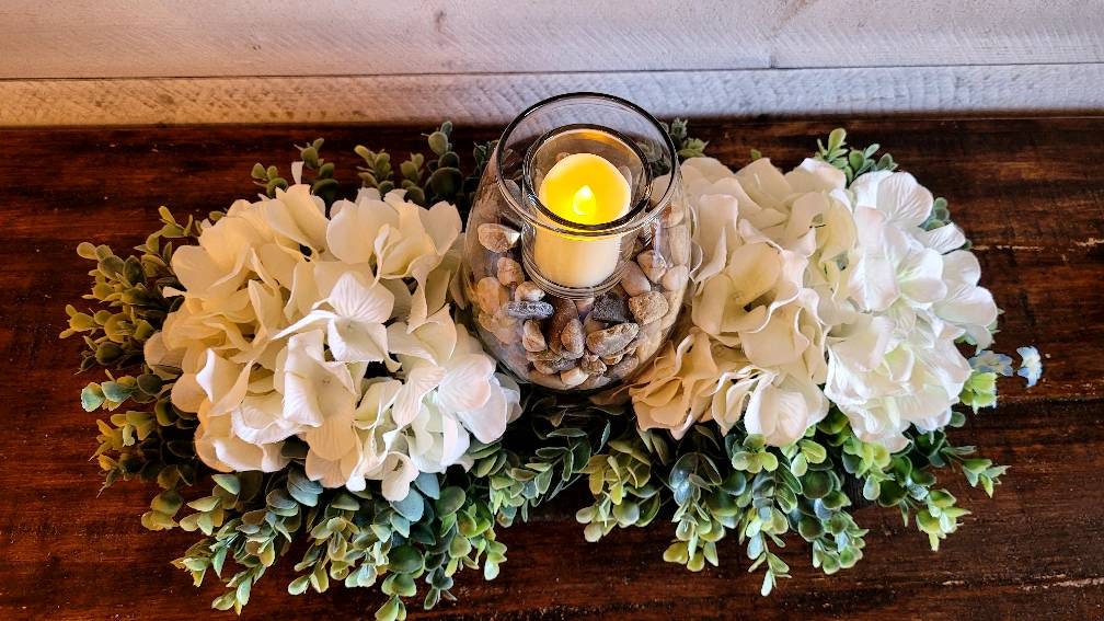 Rustic Home Decor Farmhouse Table Centerpiece Black Dough Bowl Design White Hydrangea Arrangement Votive Candle Display Wooden Bowl Collection Earth Tone Rocks Accent Seventeen Inch Length Dining Table Decoration Country Style Accent Ready