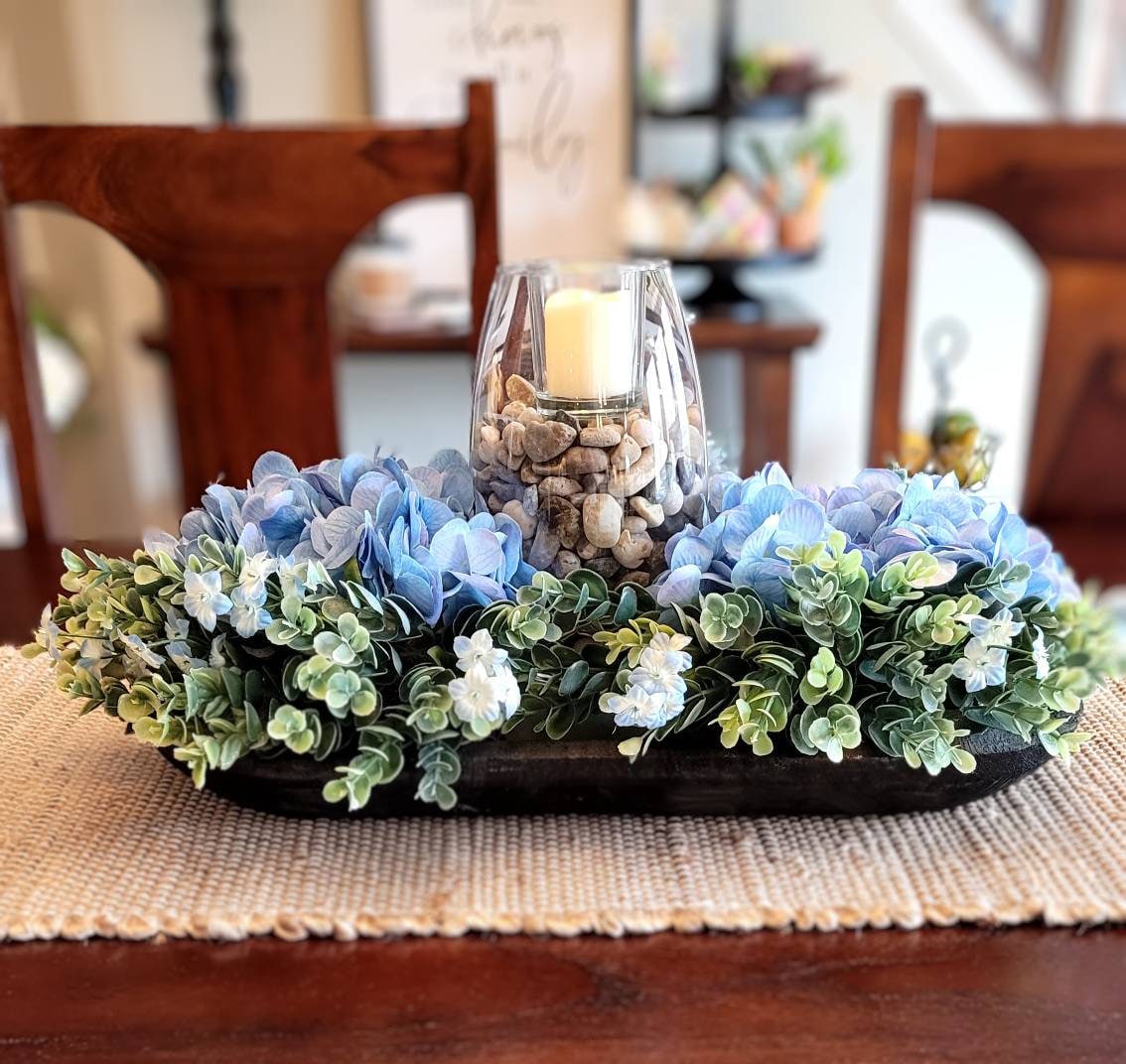 Rustic Table Centerpiece Black Dough Bowl Blue Hydrangeas Arrangement Farmhouse Style Accent Piece Dining Table Decor Modern Country Design Glass Vase Earth Toned Rocks Votive Candle Display Nineteen Inch Bowl Home Styling Mantle Decoration