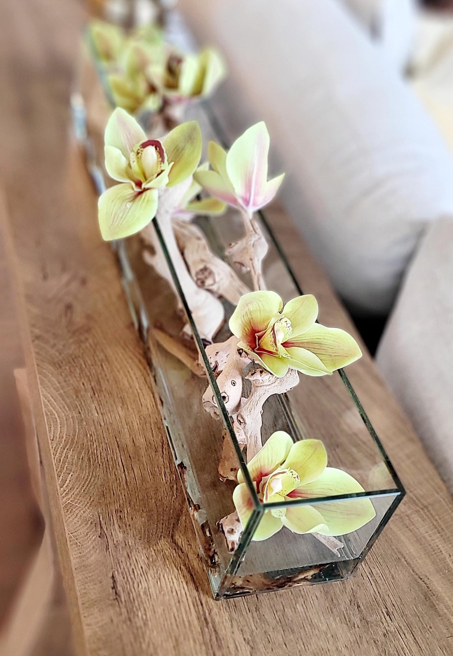 Silk Flower Centerpiece Artificial Orchid Display Glass Vase Arrangement Yellow Green Blooms Natural Driftwood Accents Stone Elements Rectangular Container Modern Dining Table Coffee Table Styling Contemporary Living Room Console Display