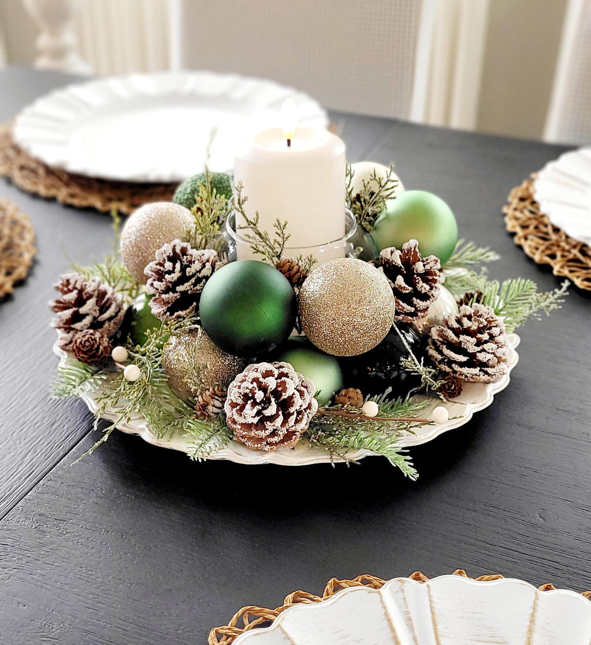 Holiday Table Centerpiece Farmhouse Christmas Styling Handmade Pinecone Arrangement White Pillar Candle Display Rustic Evergreen Sprigs Gold Ornament Styling Red Ball Display Festive Winter Season Dining Table Setting Traditional Christmas