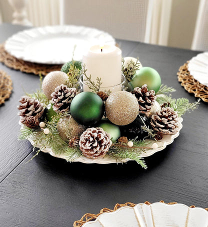 Holiday Table Centerpiece Farmhouse Christmas Styling Handmade Pinecone Arrangement White Pillar Candle Display Rustic Evergreen Sprigs Gold Ornament Styling Red Ball Display Festive Winter Season Dining Table Setting Traditional Christmas