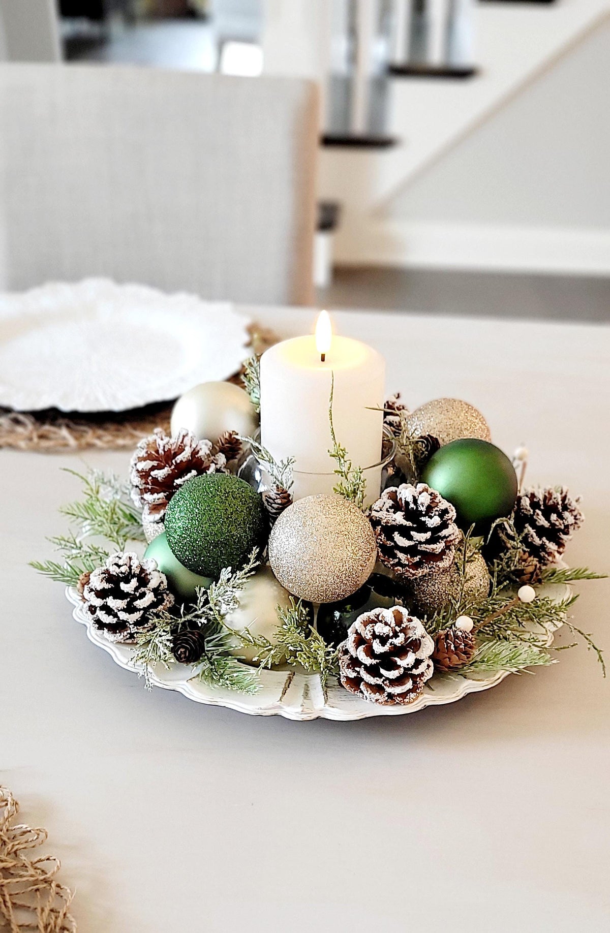Christmas Candle Centerpiece Farmhouse Style Holiday Table Styling Rustic Pinecone Arrangement Natural Evergreen Sprigs Gold Ornament Display Red Ball Styling Festive Dining Table Setting Winter Season Home Styling White Pillar Candle