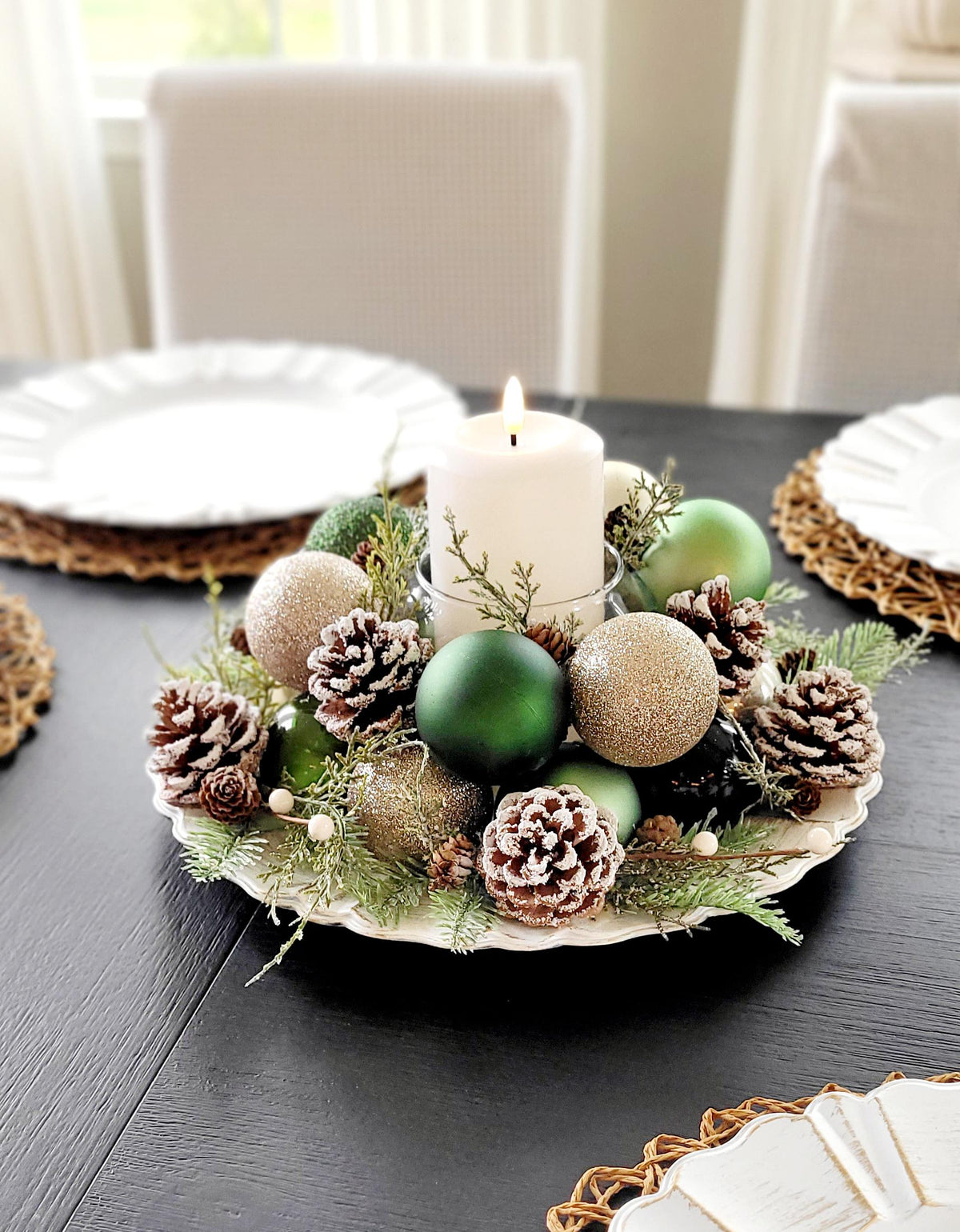 Handmade Farmhouse Christmas Centerpiece White Pillar Candle Holder Holiday Table Setting Rustic Pinecone Arrangement Red Gold Ornament Display Festive Dining Room Styling Winter Season Home Styling Evergreen Sprigs Natural Elements