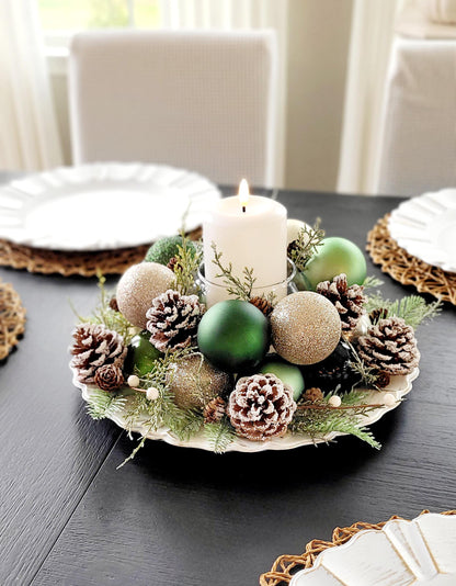Handmade Farmhouse Christmas Centerpiece White Pillar Candle Holder Holiday Table Setting Rustic Pinecone Arrangement Red Gold Ornament Display Festive Dining Room Styling Winter Season Home Styling Evergreen Sprigs Natural Elements