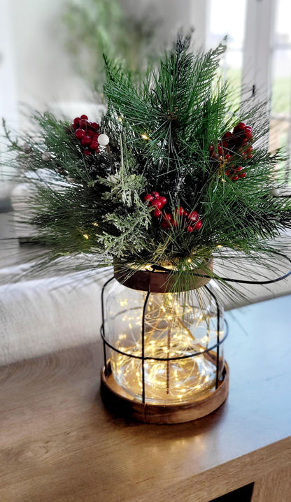 Rustic Holiday Lantern Centerpiece Christmas Table Styling Farmhouse Winter Pine Arrangement Lighted Berry Accents Warm Twinkling String Lights Indoor Seasonal Display Cozy Country Home Styling Festive Dining Room Mantel Console Arrangement