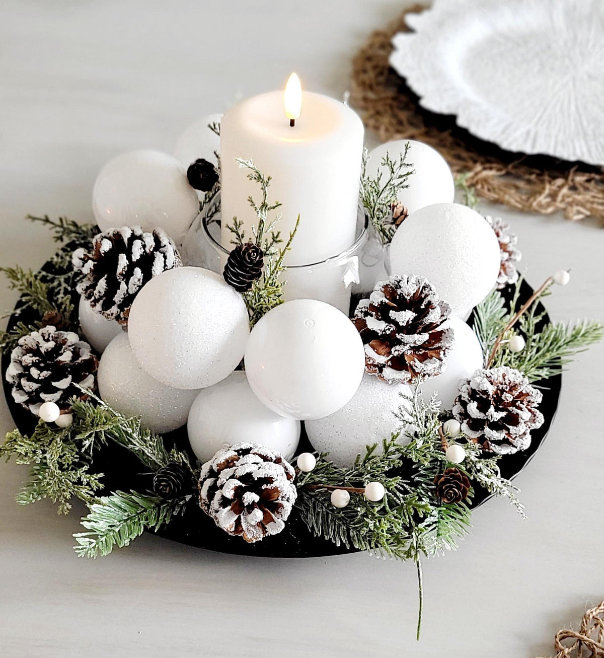 Winter Table Centerpiece White Candle Display Farmhouse Holiday Styling Snowy Pine Cone Arrangement Evergreen Sprigs Natural Elements Frosted Ornament Balls Seasonal Home Styling Elegant Christmas Table Setting Rustic Winter Wedding