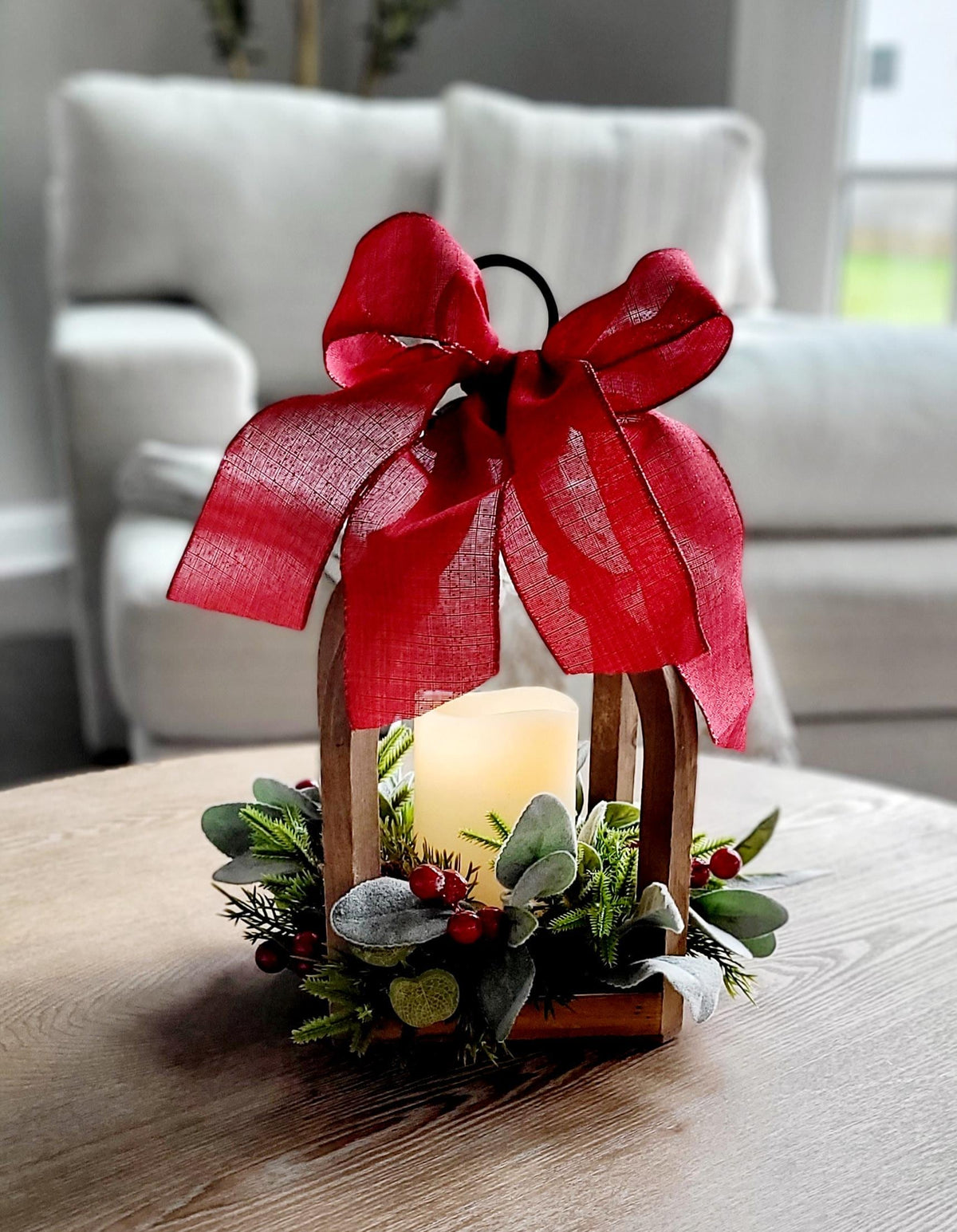 Farmhouse Christmas Centerpiece Wooden Lantern Design Rustic Holiday Table Setting Flameless LED Candle Battery Operated Safe Lighting Red Berry Pine Greenery Festive Ribbon Bow Arched Handle Frame Winter Mantel Display Seasonal Dining Room