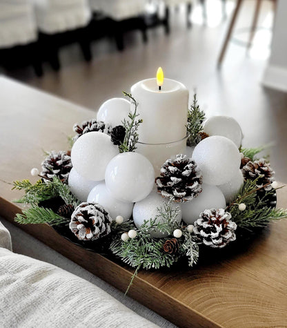Elegant White Winter Centerpiece Farmhouse Christmas Candle Display Frosted Ornament Ball Arrangement Natural Pine Cone Styling Evergreen Sprigs Accents Snowy Holiday Table Setting Rustic Seasonal Styling Winter Wedding Centerpiece Display